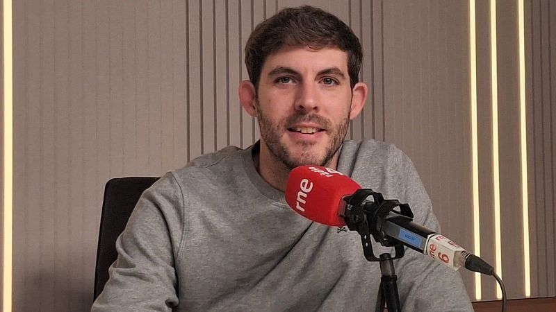 El comunicador Carles Capella sonr�e en un estudio de radio ante un micr�fono de RNE con panel ac�stico de fondo.
