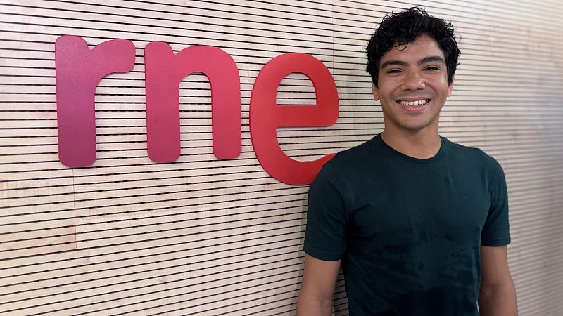 El bailaor Gabriel Matías sonríe en un estudio de radio, junto al logotipo rojo de RNE y una pared de paneles de madera.