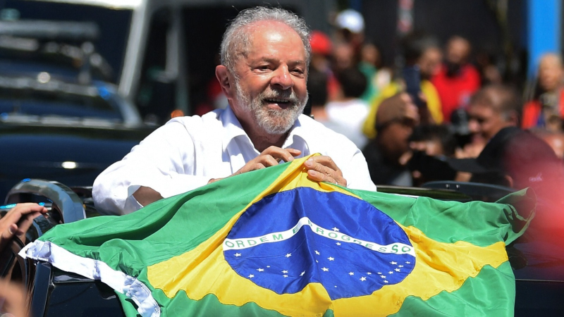El pol�tico Luiz In�cio Lula da Silva sostiene una bandera de Brasil con el lema �ORDEM E PROGRESSO� durante un evento al aire libre.