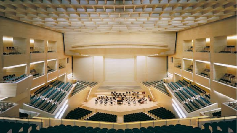 Gran auditorio sinf�nico vac�o con escenario de madera, butacas oscuras y sofisticado techo ac�stico de casetones.