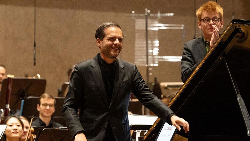 El director Pablo Heras-Casado sonr�e y extiende la mano hacia un piano mientras el compositor Enno Poppe aplaude en el escenario.