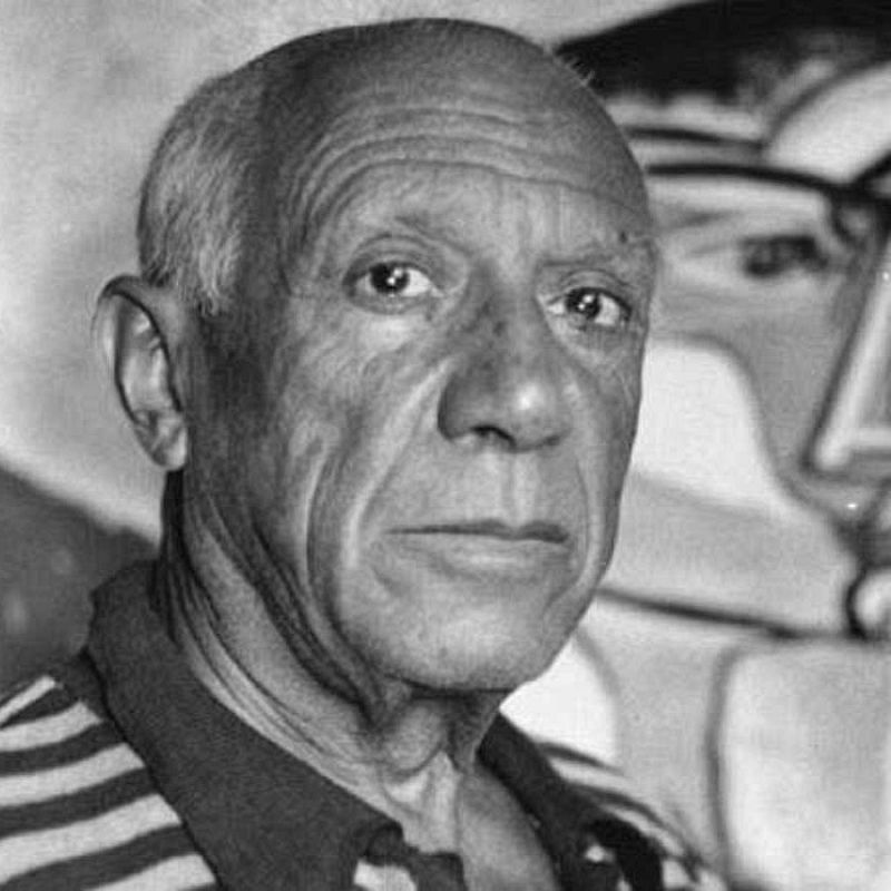 Retrato en blanco y negro de un hombre con cabello corto y arrugas, vistiendo una camisa a rayas, con una obra de arte abstracta de fondo.