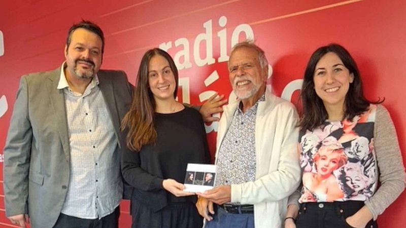 Cuatro personas posan sonrientes en un estudio con fondo rojo y el logotipo de Radio Cl�sica, sosteniendo un disco compacto durante la presentaci�n de un �lbum musical.