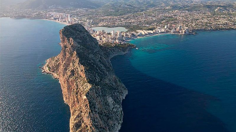 Vista aérea panorámica del Peñón de Ifach en Calpe, destacando su imponente formación rocosa junto al mar y los edificios de la costa.