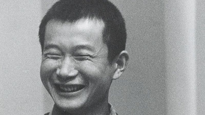Fotograf�a en blanco y negro de un hombre joven sonriendo alegremente con los ojos cerrados.