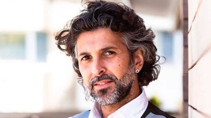 Primer plano del cantaor Arc�ngel mirando a la c�mara, con cabello oscuro y canoso, barba recortada y camisa blanca sobre fondo difuminado.