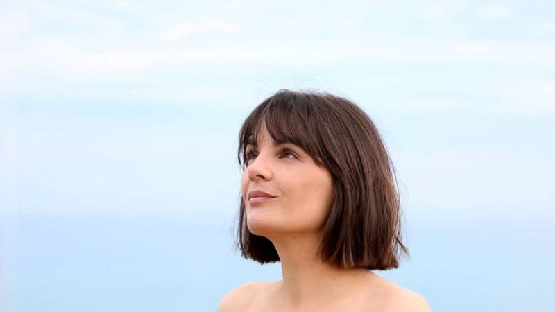 Primer plano de la cantante Anne Lukin al aire libre con melena corta y una expresión serena bajo un cielo azul.