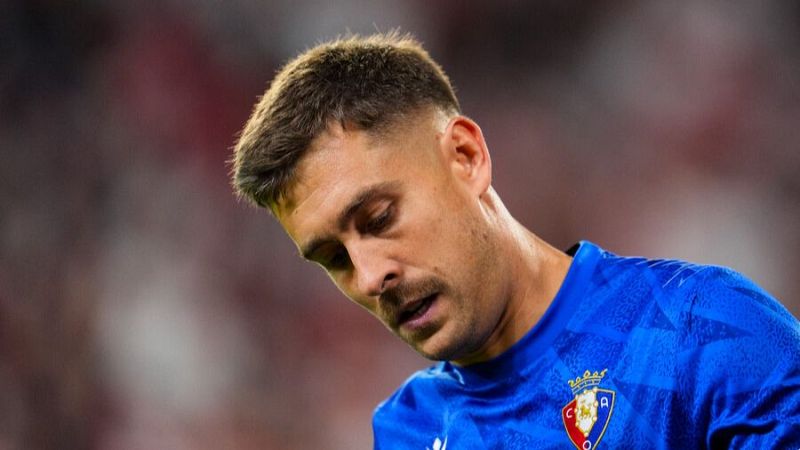 Plano medio corto del portero Aitor Fernández con la equipación azul del Osasuna y expresión seria en el estadio.