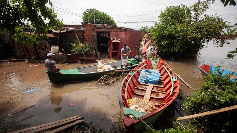 Dos hombres navegan en una canoa por una calle inundada en Corrientes, Argentina, tras el desbordamiento del río Paraná debido a las fuertes lluvias.