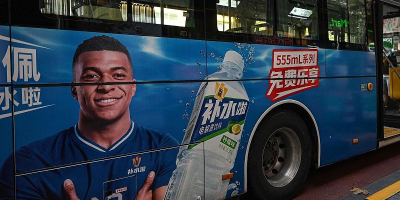 Autob�s urbano con publicidad lateral que muestra al futbolista Kylian Mbapp� y una botella de bebida hidratante con caracteres chinos.