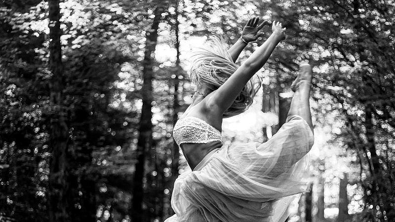 Bailarina en pleno salto art�stico dentro de un bosque, con el cuerpo arqueado y vistiendo una falda de tul vaporosa.