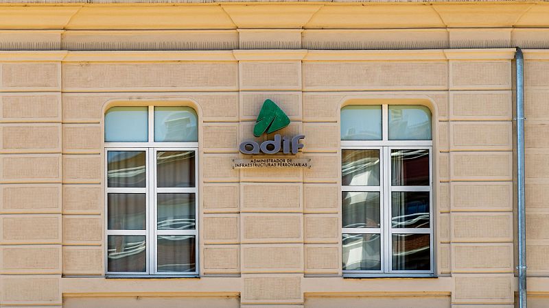 Fachada de edificio institucional con el logotipo corporativo de Adif en relieve en el centro, flanqueada por dos grandes ventanales simétricos.