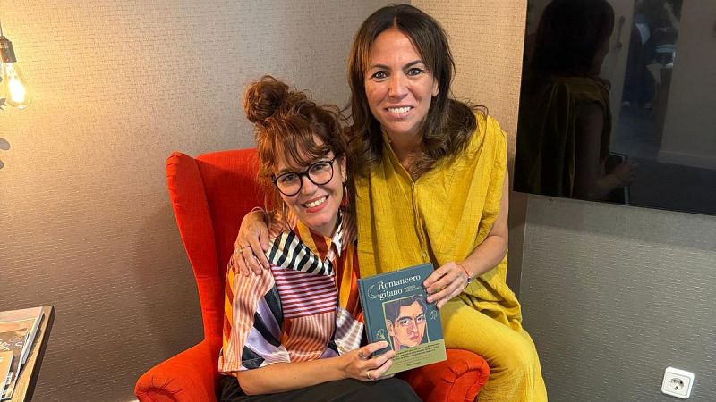 Dos mujeres sonrientes sostienen un libro titulado �Romancero gitano�, una sentada en una butaca roja y otra apoyada en su hombro.
