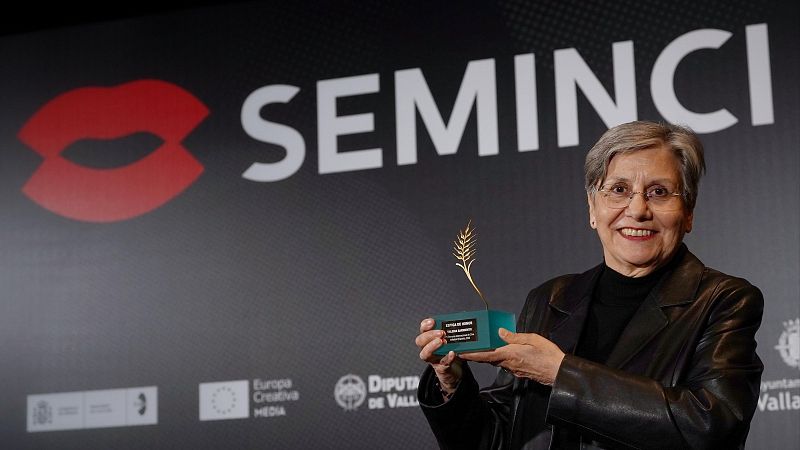 La cineasta Valeria Sarmiento sonríe sosteniendo la estatuilla de la Espiga de Honor frente al panel del photocall del festival de cine.