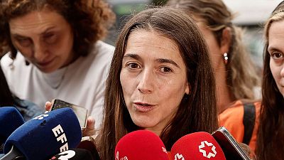 La política Isabel Serra habla ante los medios en una comparecencia de prensa rodeada de numerosos micrófonos de periodistas.
