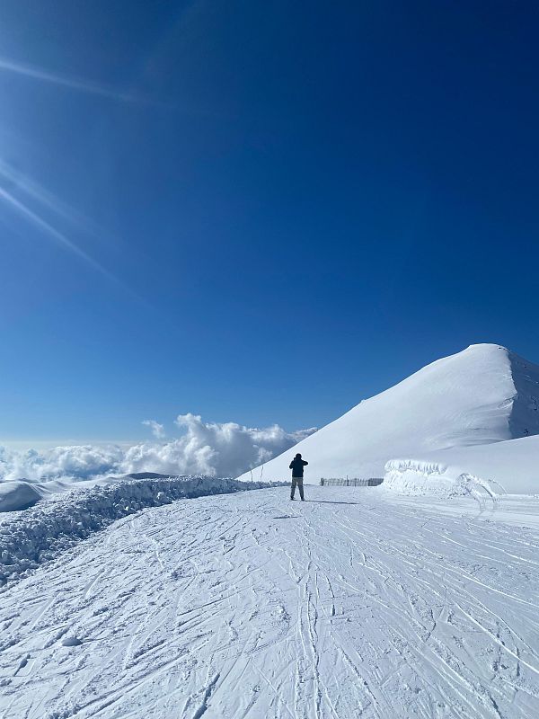 Pista de esquí nevada en Boí Taüll con un esquiador, cielo azul soleado y nieve brillante.  Marcas de esquí indican actividad reciente.