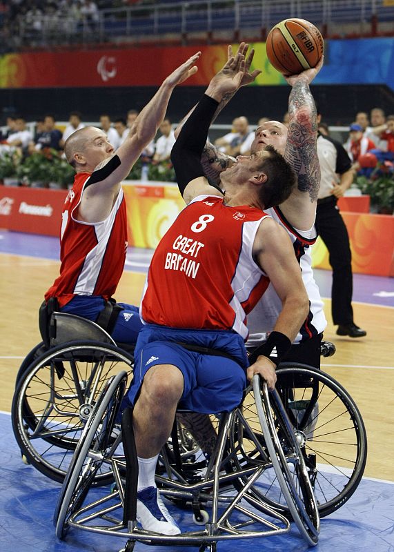Joe Chambers de EE.UU, Terence Bywater y Simon Munn del Reino Unido luchan por el balón, en el partido de baloncesto que les ha enfrentado por la medalla de bronce.