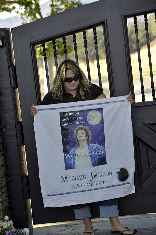 Una fan sujeta un cartel con una fotografía del cantante frente a la puerta de Neverland, California.