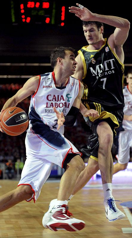 El pívot lituano del Real Madrid, Darjus Lavrinovic, intenta evitar el avance del escolta del Caja Laboral Baskonia, Carl English.