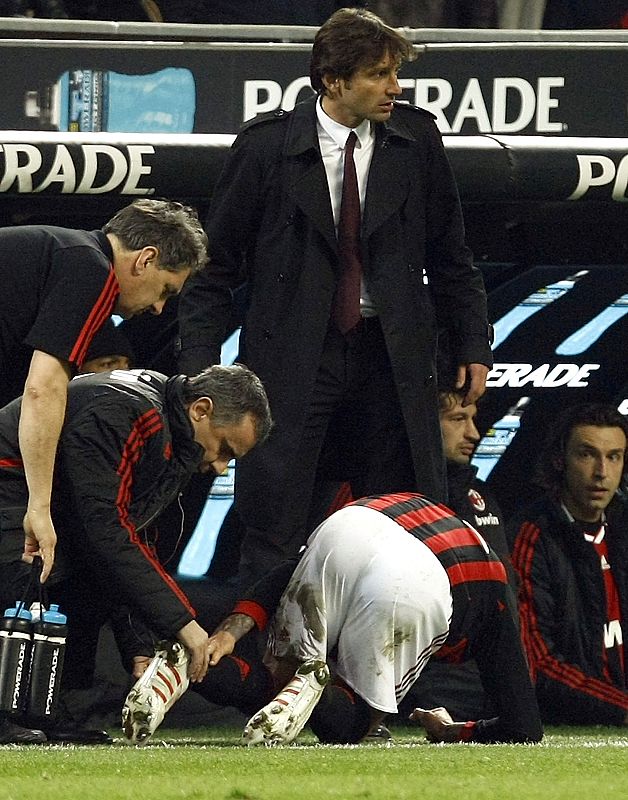 Un fisioterapeuta del AC Milan atiende a David Beckham en la banda.