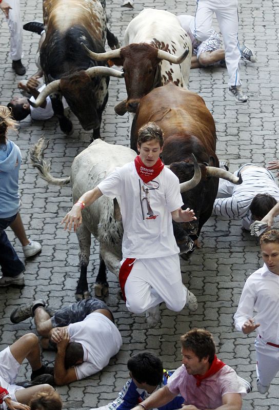 A runner runs in between the horns of a Penajara fighting bull before the first day of the running of the bulls during the San Fermin festival in Pamplona
