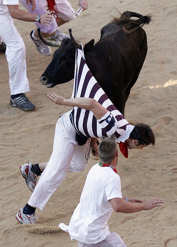 A reveller is tossed by a fighting cow during festivities in the bull ring during the San Fermin festival in Pamplona