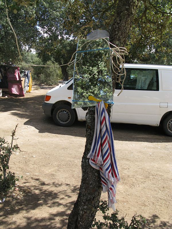 Un espejo atado a un árbol hace de improvisado lavabo en el campamento rumano