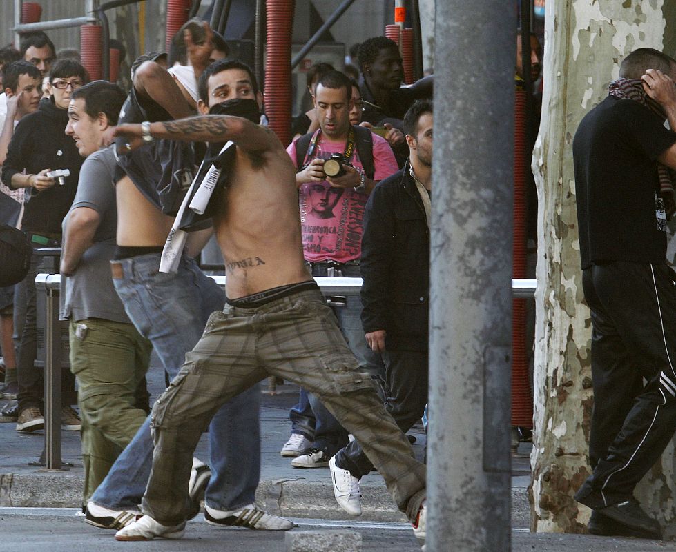A protester throws a rock at riot police during a general strike in central Barcelona