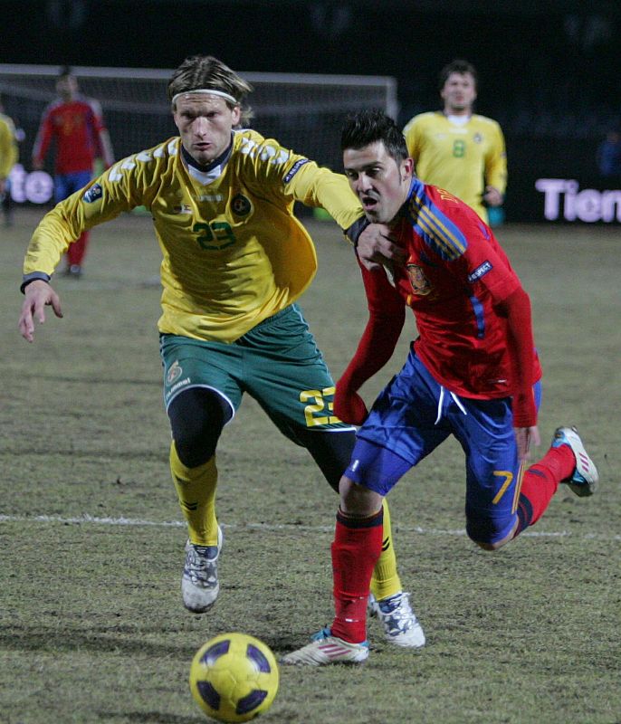 El jugador de Lituania Marius Stankevicius lucha por el balón con David Villa, de España.