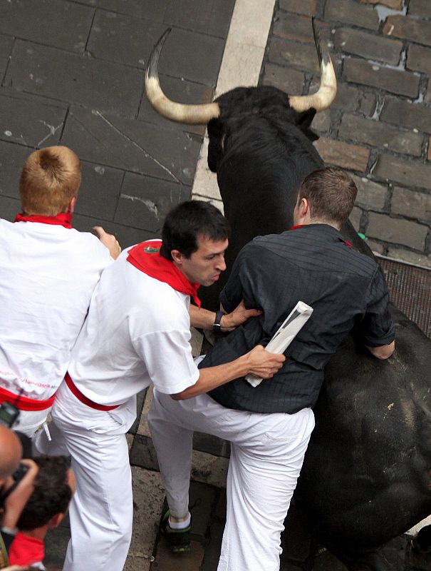 Uno de los toros junto a los corredores en la jornada mas accidentada hasta el momento de los sanfermines 2012