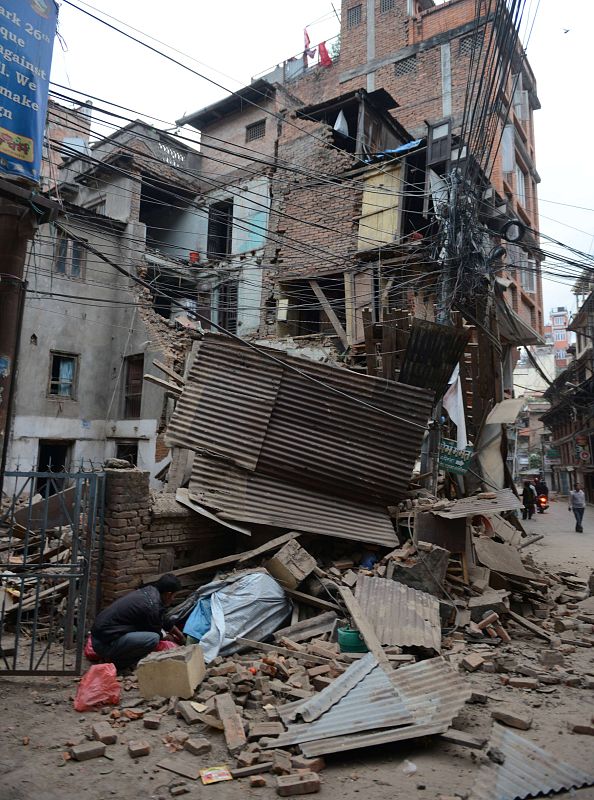 Un hombre, parte inferior izquierda, mira a través de los escombros tras el terremoto que ha dejado más de 800 muertos.