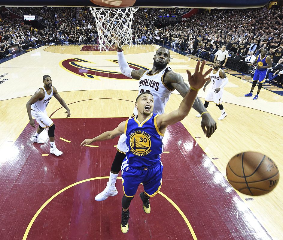 El jugador de los Warriors Stephen Curry (en primer plano) lucha por el balón con LeBron James (atrás) de los Cavaliers (16 de junio de 2016)