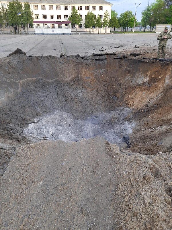 Un soldado uniformado rodea un cráter en medio de un patio producido por un bombardeo ruso en Desna, Chernígov.