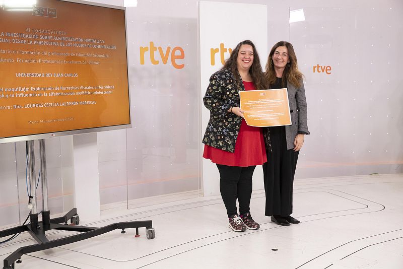 Dos mujeres, una de ellas la investigadora Lourdes Cecilia Calderón Mariscal, posan con un diploma de Impulsa Visión en un estudio de televisión de RTVE.