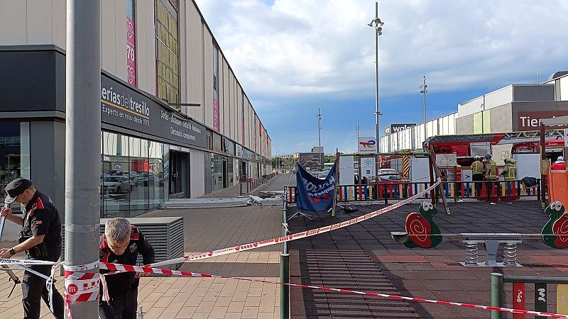Agentes de policía acordonan una zona con escombros tras un accidente, cerca de un parque infantil.  Se ve un camión de bomberos al fondo.