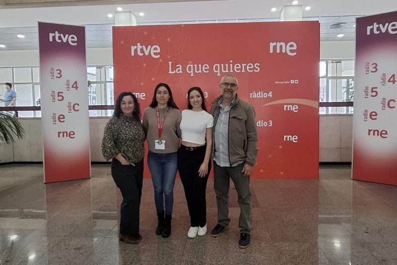 Cuatro personas se encuentran frente a dos carteles con logos de RTVE y RNE, promocionando programas de radio. Los carteles mencionan emisoras como Radio 3 y Ràdio 4, sugiriendo un evento o colaboración.