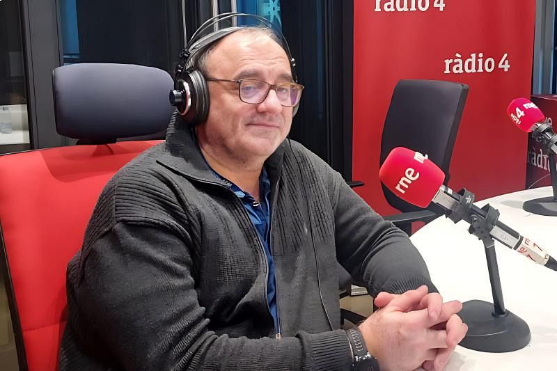 Antonio Turiel, con gafas y auriculares, se encuentra en un estudio de radio, llevando una chaqueta oscura y camisa azul. Se aprecia un panel rojo con el logo de una emisora y la inscripción "ràdio 4", además de dos micrófonos.