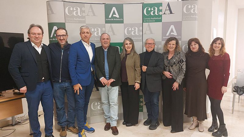 Un grupo de nueve personas posa para una foto, posiblemente miembros de un jurado. Los individuos visten ropa formal y casual, con un panel con logotipos al fondo.