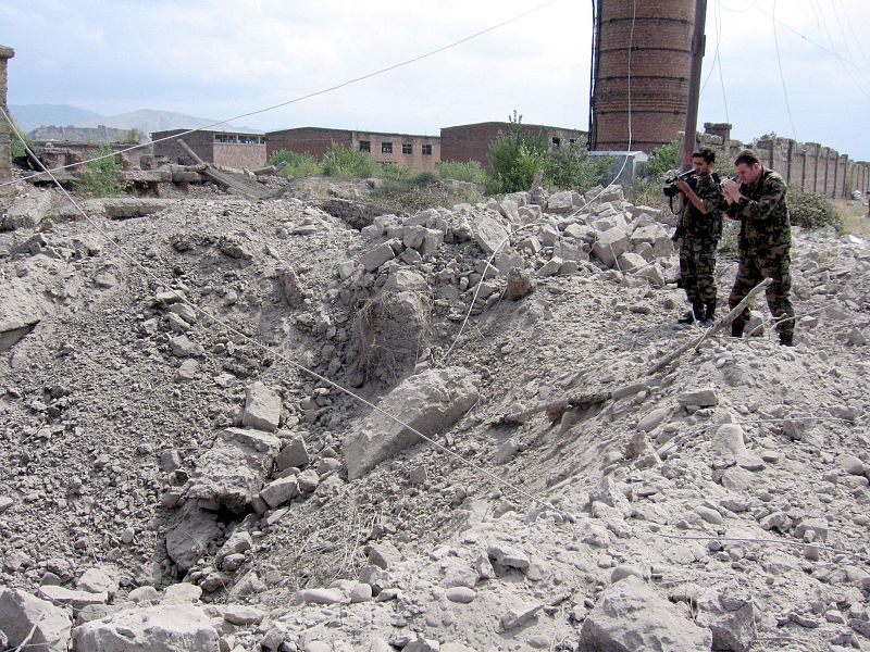 Dos militares georgianos toman imágenes del agujero que ha dejado una bomba lanzada desde un avión en la ciudad de Gori (Georgia).