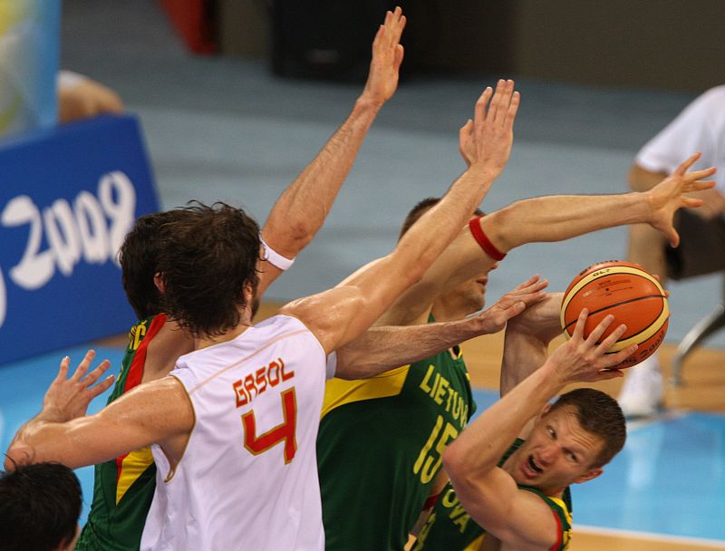 El lituano Mindaugas Lukauskis controla el balón ante el bloqueo del español Pau Gasol.