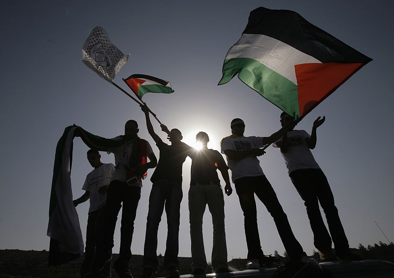 Palestinians wave flags as await arrival of prisoners at checkpoint outside Ramallah