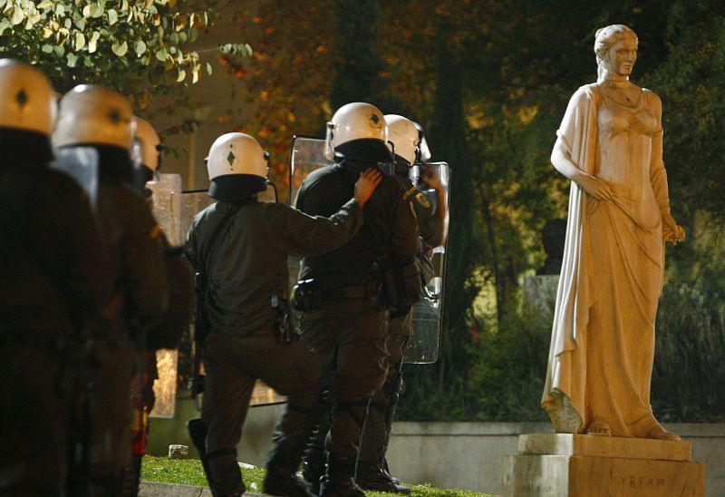 Los agentes toman posiciones junto a una estatua situada cerca de la universidad de derecho en Atenas.
