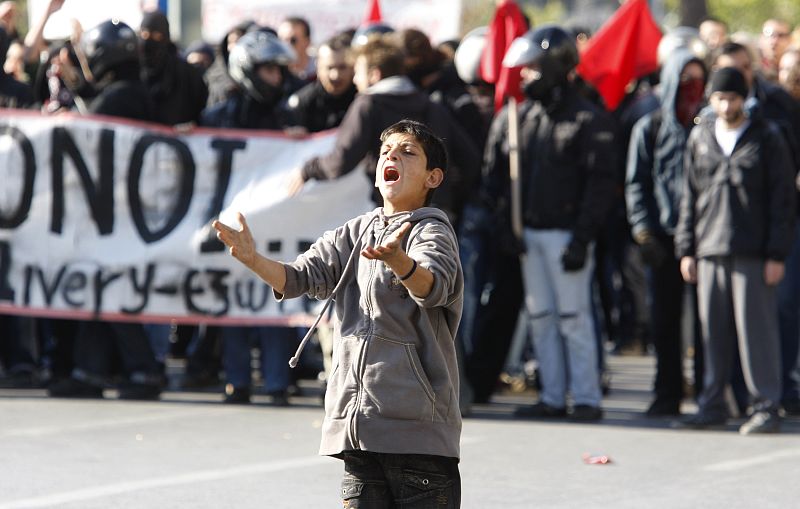 Un niño increpa a la policía en las calles de Atenas durante la huelga general.