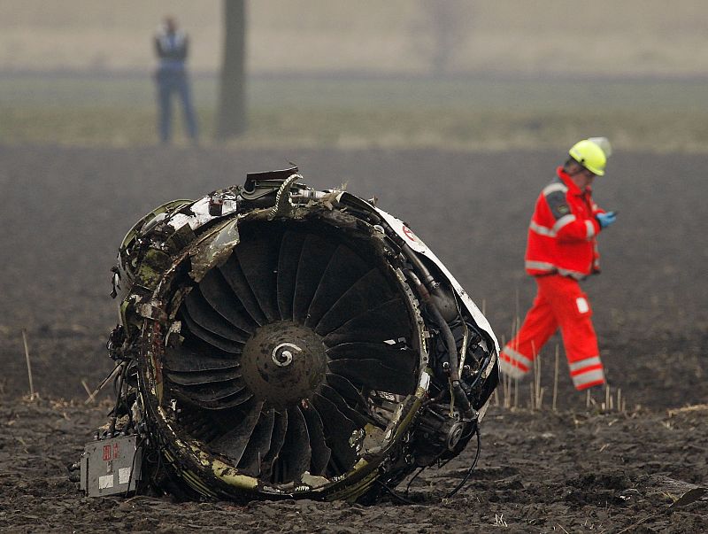 Un bombero camina junto al motor del avión siniestrado
