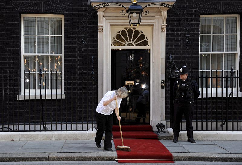 Una mujer barre la alfombra roja antes de la llegada del presidente estadounidense