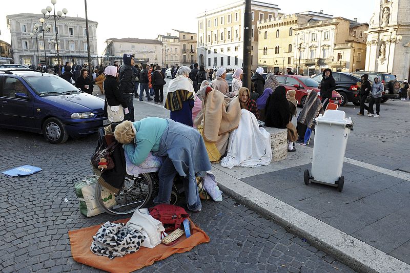 People cover with blankets as the gather in a square after an earthquake in Aquila