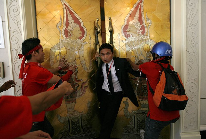 Un miembro de la cumbre de la ASEAN intenta evitar que los manifestantes entren en una de las salas de la cumbre.