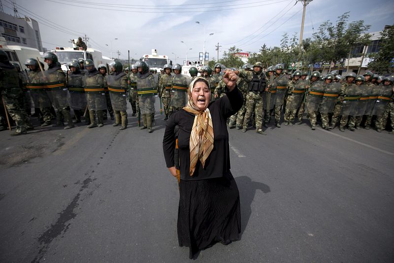 Una mujer musulmana  de etnia uigur protesta ante una columna de  antidisturbios durante una manifestación convocada en Urumqi
