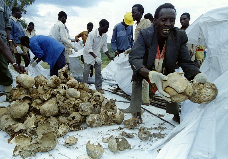 Rwandans place the skulls of several hundred Tutsi civilians into bags after a memorial for approxim..