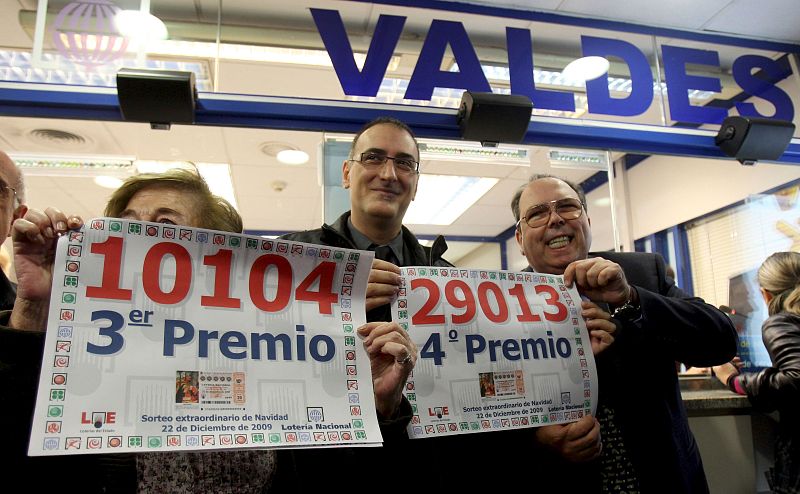 Los propietarios de la administración de lotería Valdés, en Barcelona, Jordi y María Teresa, muestran los carteles con los números 10.104, tercer premio, y 29.013, cuarto.